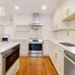 Cream shaker kitchen with gold hardware and marble backsplash