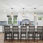 Kitchen island with counter stools and white shaker cabinets