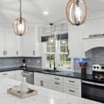 Kitchen with white shaker cabinets, dark countertops, and marble-look island
