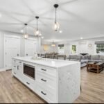 Open-plan kitchen island with white cabinetry beside a living area