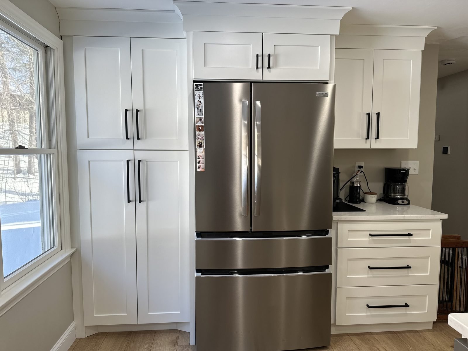 White shaker pantry cabinets surrounding a stainless refrigerator