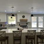 White shaker kitchen with large quartz island and black-and-brass pendant lights