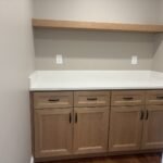 Laundry room cabinetry in maple with floating wood shelf and white countertop